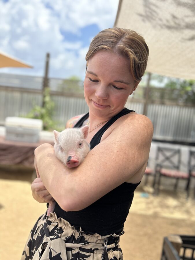 woman at pig petting zoo holding a piglet in San Antonio, TX